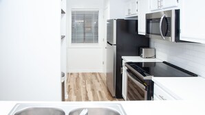 Una cocina moderna con armarios blancos, electrodomésticos de acero inoxidable y piso de madera.