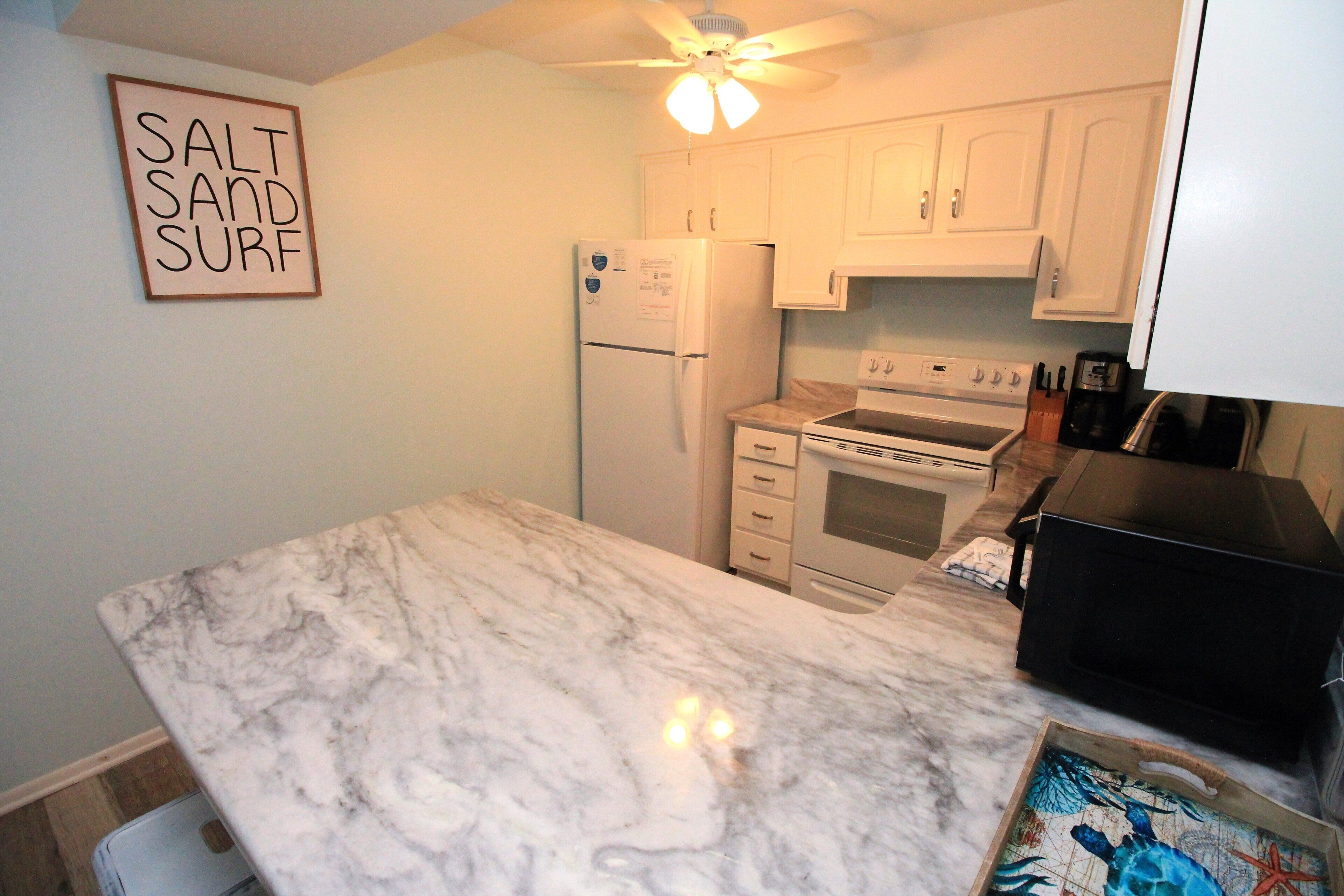 A kitchen with white cabinets, a refrigerator, an oven, and a countertop.