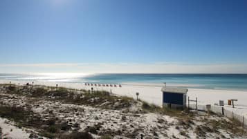 A beach with a small blue building, sandy dunes, and the ocean.