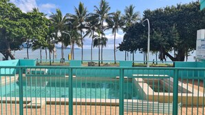 A swimming pool with a view of the sea and palm trees. - Emthree Seaside Apartments (North Ward)