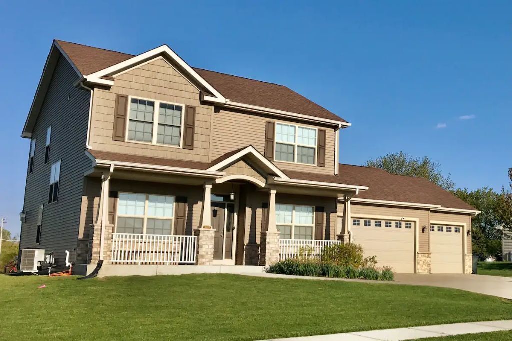 A two-story house with a front porch, a garage, and a well-maintained lawn.