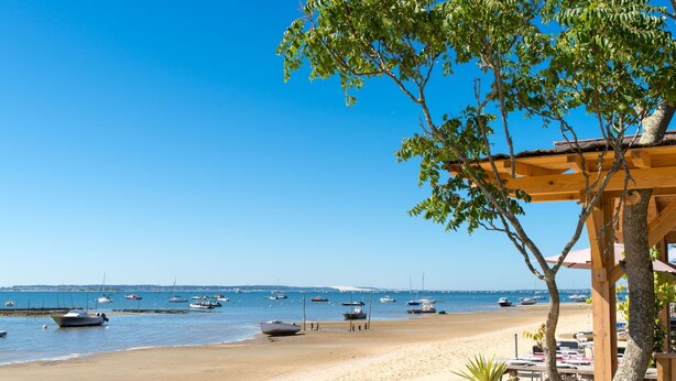 A beach with boats, a wooden structure, and a clear sky.