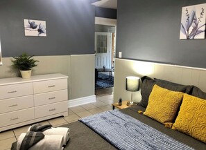 Relax in a serene bedroom with a comfortable bed, bedside table, and calming artwork.