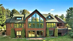 A large log cabin with multiple windows, a covered porch, and a well-maintained lawn.