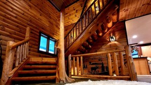 A log cabin interior with a staircase, a fur rug, and a mural of a moose.