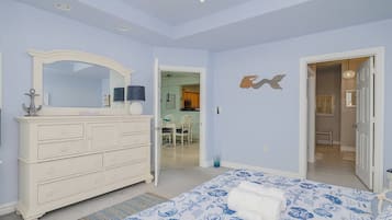 Een slaapkamer met een bed, een dressoir en een spiegel. Deur naar een andere kamer.