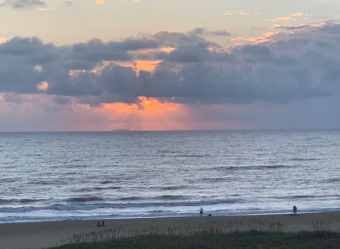 A beach with a view of the ocean and a sunset.