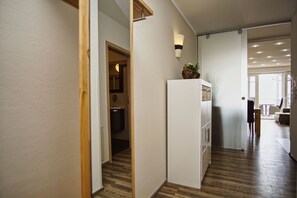 A hallway with wooden flooring, a white cabinet, and a wall-mounted light fixture. - Vacation Apartment Near the Harbor with a View of the Sea - Hafenresidenz Lauterbach FeWo 2-2 - (Putbus)