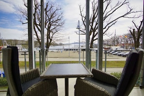 Ein überdachter Außenbereich mit Tisch und Stühlen, mit Blick auf einen Parkplatz und ein großes Gebäude.
