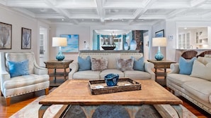 A spacious living room with a large sofa set, a coffee table with a tray, and a chandelier. - Center Of It All: 454-Cv  Sea Captain's Estate with Heated Pool and Pickle Ball Court (Centerville)
