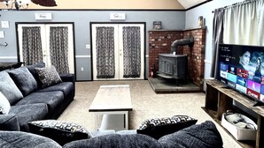 Un salon comprenant un canapé, une table basse, une cheminée, un téléviseur et un ventilateur de plafond.