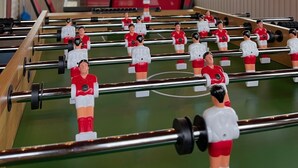 Une table de baby-foot dans une pièce avec des poutres en bois et de grandes fenêtres.