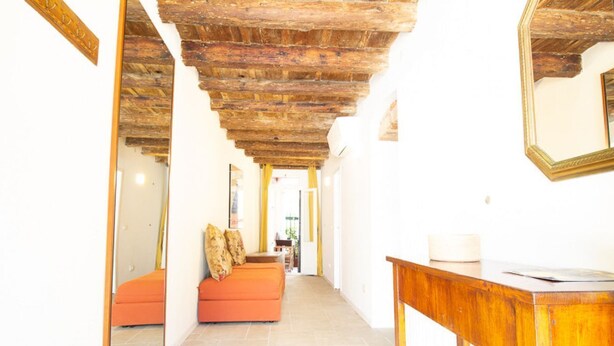 A hallway with a wooden ceiling, orange sofa, and a wooden table. - Apartment Campaniel Veneziacentopercento (Venezia)