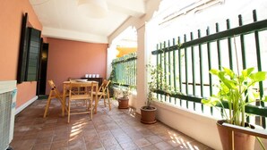 A patio with a table and chairs, potted plants, and a green fence. - Apartment Campaniel Veneziacentopercento (Venezia)
