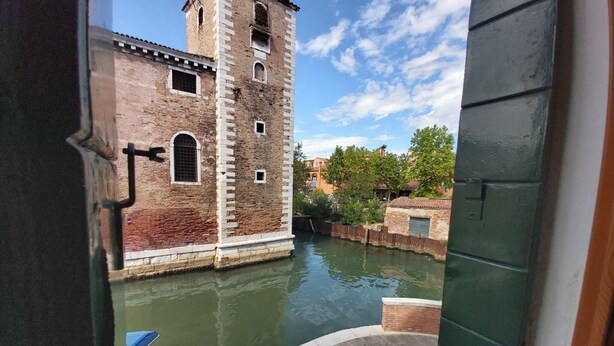 Un canal con un edificio de ladrillo y una torre.