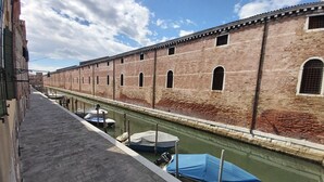 Un canal con barcos amarrados a la derecha, un edificio de ladrillo a la izquierda y un cielo despejado.