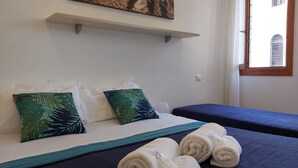 Habitación de hotel con cama, almohadas, una ventana y toallas.