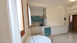 Cocina compacta con armarios verde agua, un microondas y una campana extractora de acero inoxidable.