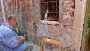 A man sitting on a wooden chair outside a stone building, engaged in fishing. - Ca' Riello Apartment - Veneziacentopercento (Venezia)