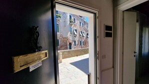A door with a brass handle and a nameplate, leading to a balcony with a view of a building. - Ca' Riello Apartment - Veneziacentopercento (Venezia)