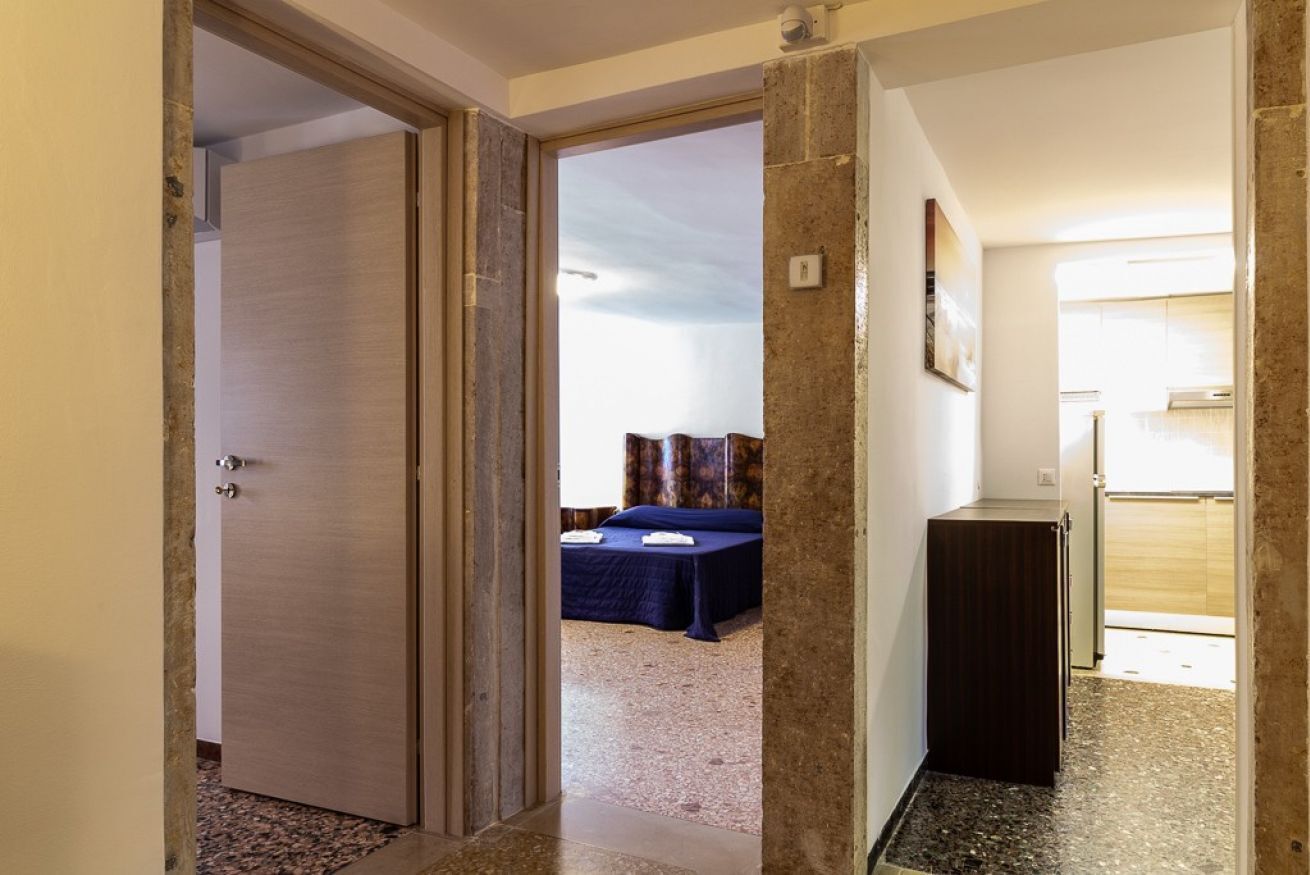 A hotel room with a bed, a desk, and a view of the outside.