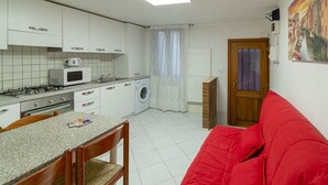 A compact kitchen with white cabinets, a microwave, a stove, and a washing machine. - Picenin Apartment - Veneziacentopercento (Venezia)