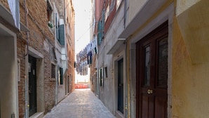 Un estrecho callejón con pavimento de piedra, flanqueado por edificios con puertas y contraventanas de madera.