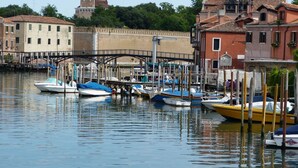 Un canal con barcos amarrados, un puente y edificios de arquitectura tradicional.