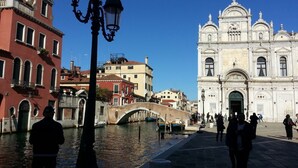 Un canal amb un pont, edificis a ambdós costats i una església blanca destacada amb arquitectura ornamentada.