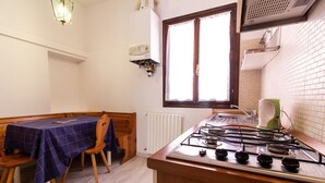 Cuina amb fogó de gas, radiador i finestra amb cortines.