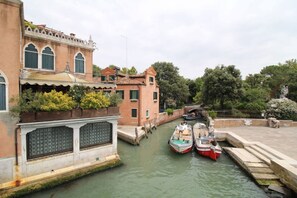 Un canal étroit où sont amarrés des bateaux, bordé de bâtiments historiques aux fenêtres en arc de cercle, avec un pont en arrière-plan.