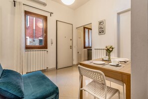 Uma cozinha compacta com mesa, cadeiras e janela com cortinas.