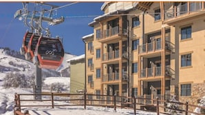 A multi-story hotel with balconies, a ski lift, and a snowy landscape.