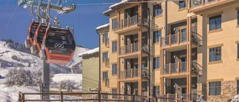 A multi-story hotel with balconies, a ski lift, and a snowy landscape.