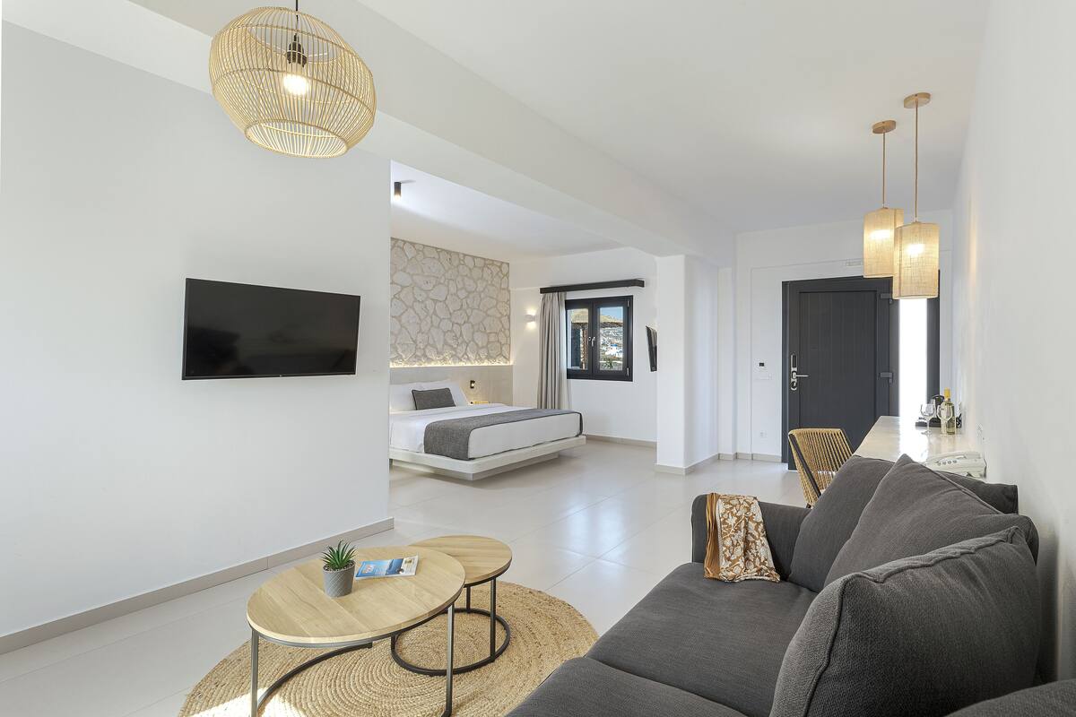 Un salon moderne avec un canapé, une table basse, un téléviseur et un lit en arrière-plan.