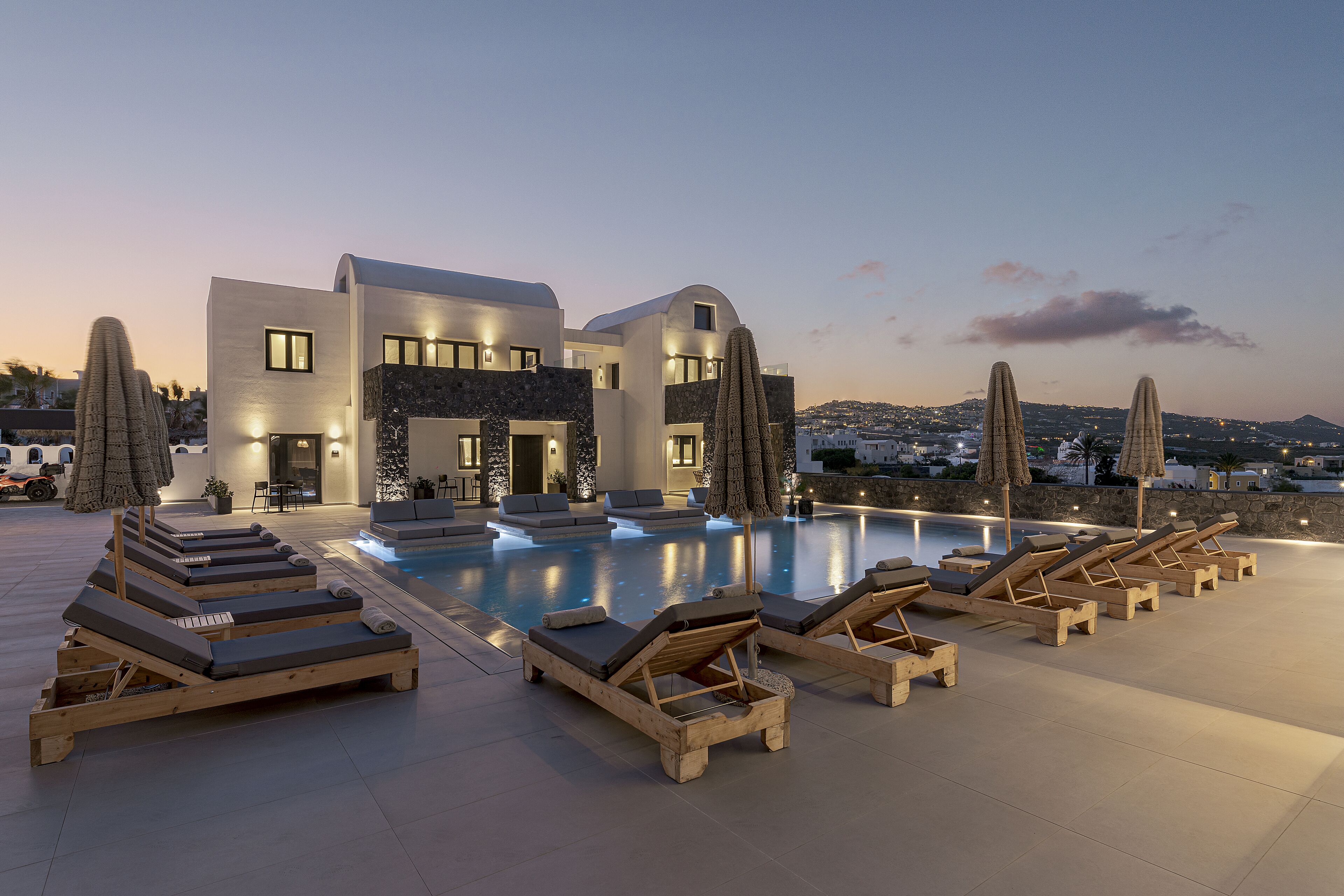 A modern villa with a pool, sun loungers, and a view of the landscape.