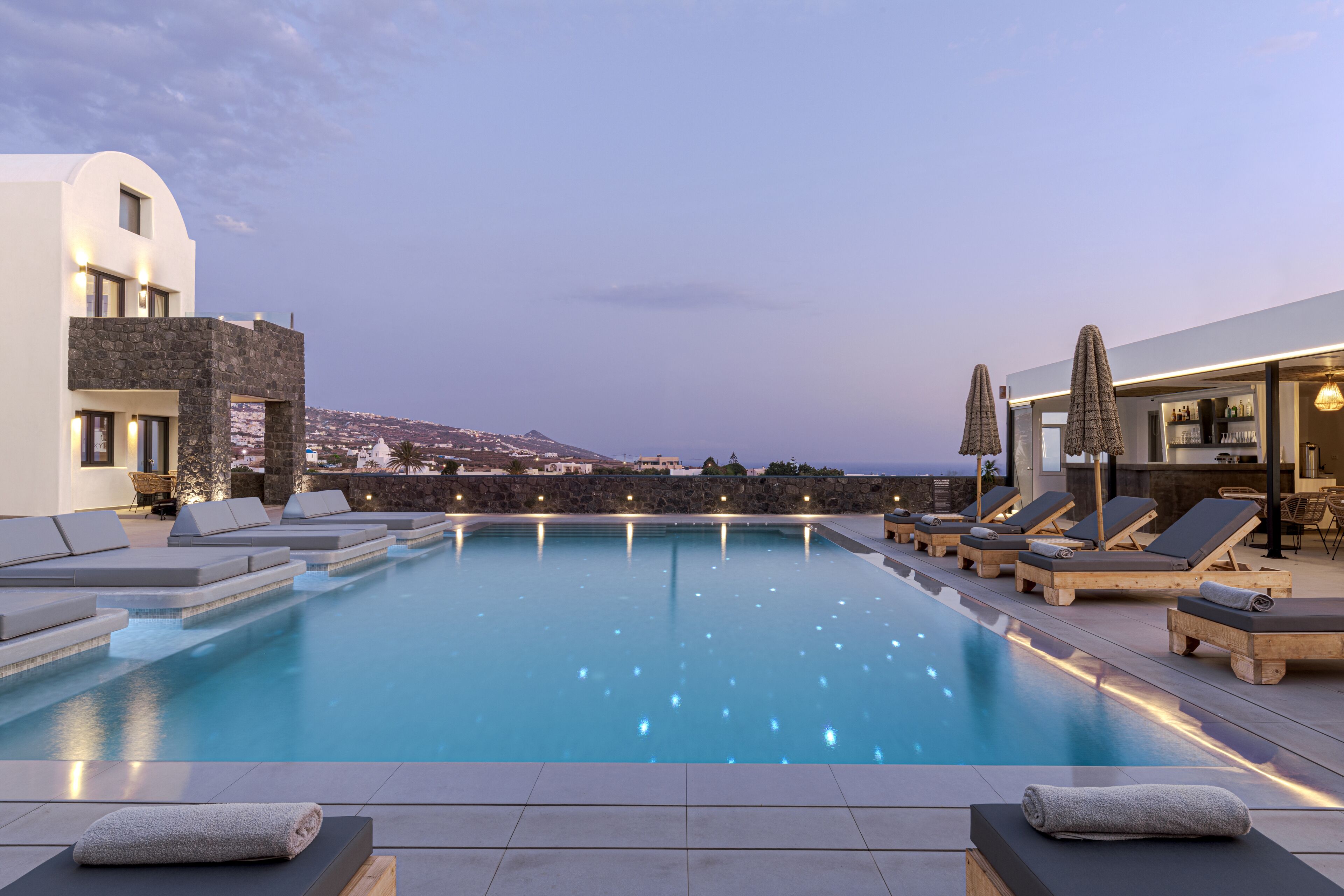 A pool area with lounge chairs and a view of the sea.