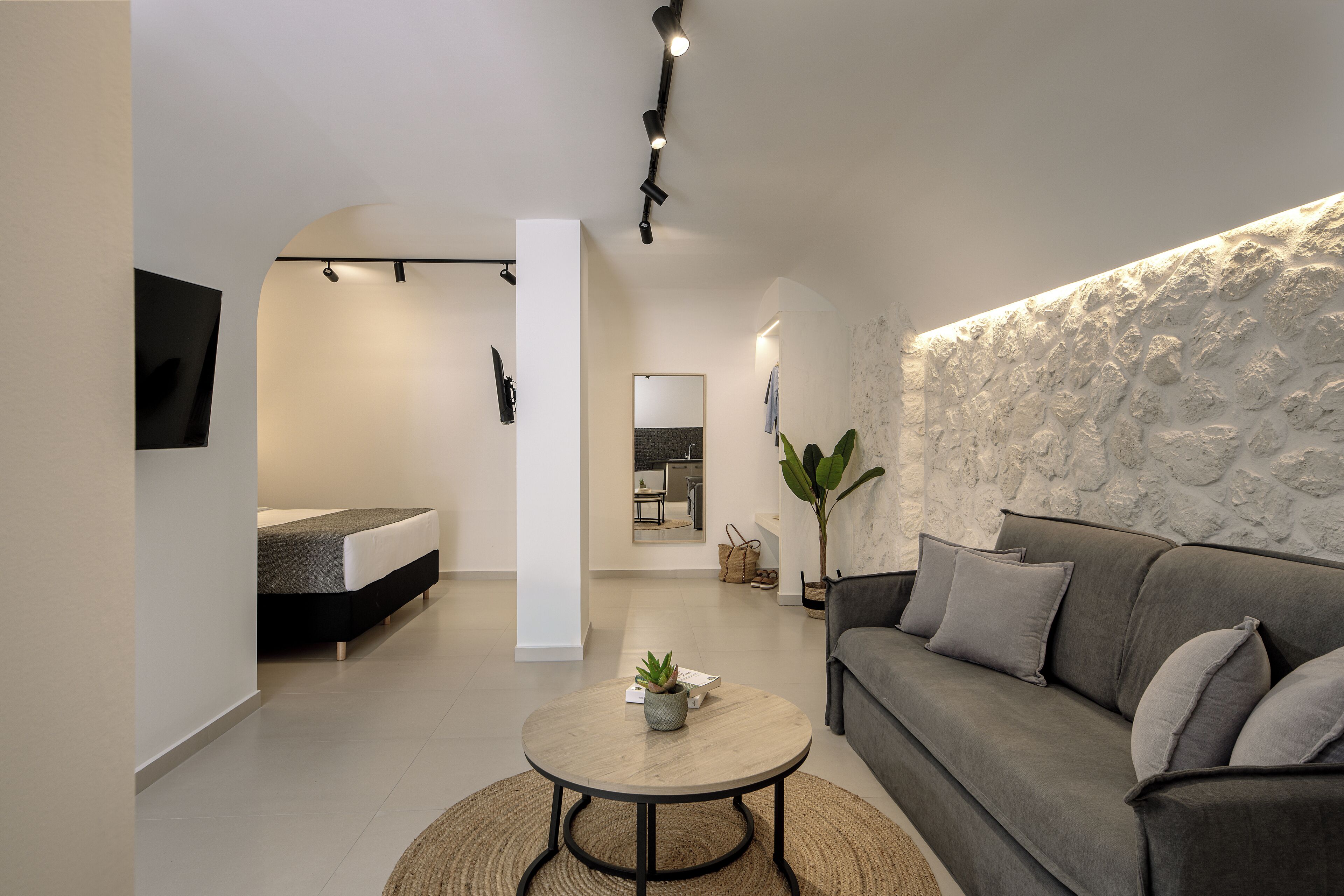 Un salón moderno con un sofá, una mesa de centro y un televisor montado en la pared.