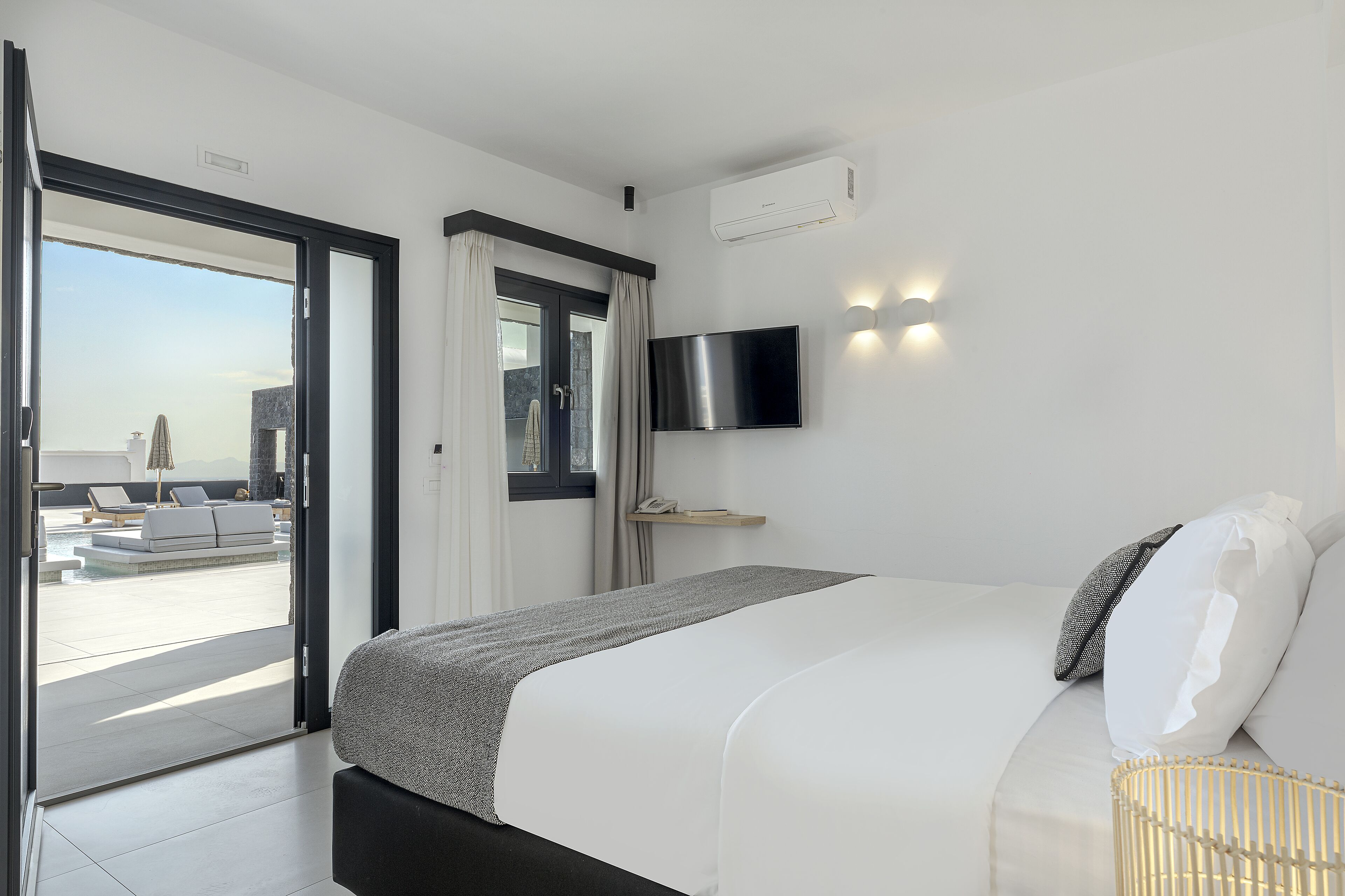 Habitación de hotel moderna con cama, televisión y vistas a un área de piscina al aire libre.
