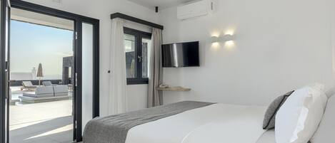 Habitación de hotel moderna con cama, televisión y vistas a un área de piscina al aire libre.