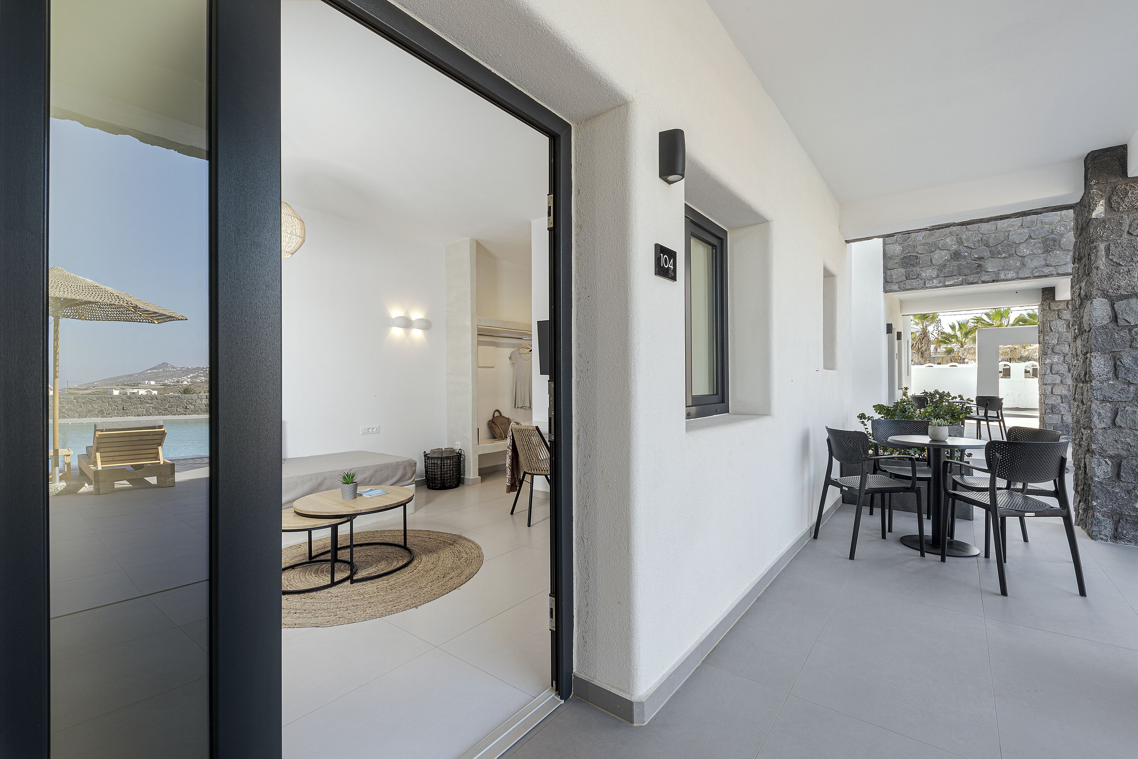 A modern interior with a dining area, a stone accent wall, and a view of the sea.