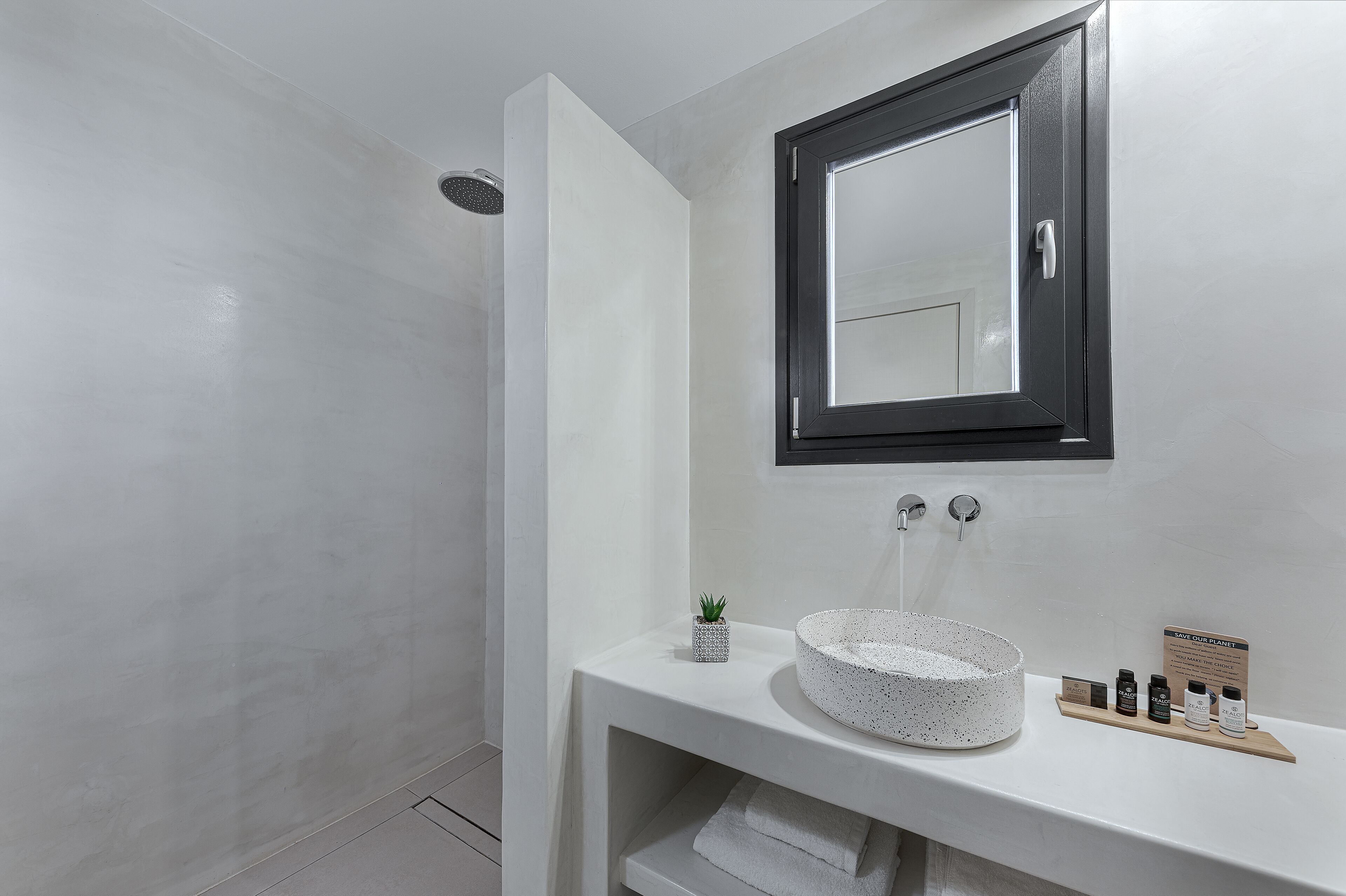 A modern bathroom with a white sink, a mirror, and a shower.