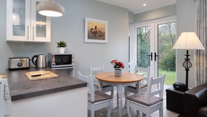 A modern kitchen with a wooden island, white cabinetry, and a dining area with a round table and chairs. - Cottage 420 - Clifden - sleeps 4 guests  in 2 bedrooms (Clifden)
