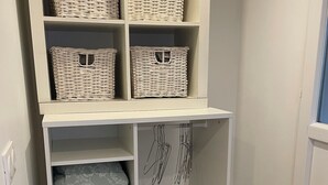 Un módulo de almacenamiento blanco con cestas de mimbre y un perchero.
