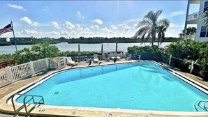 Una piscina rettangolare con vista su un lago e palme.
