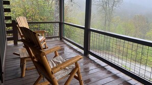 En inglasad veranda med trämöbler och utsikt över ett skogsområde.