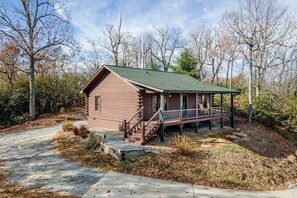 A log cabin with a porch and a staircase leading to the entrance.