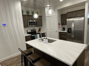 Una cocina moderna con una isla grande, electrodomésticos de acero inoxidable y armarios de madera.