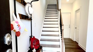 Un couloir avec un banc en bois, un sac rouge et un jouet en peluche.