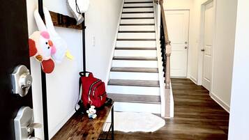 A hallway with a wooden bench, a red bag, and a plush toy.